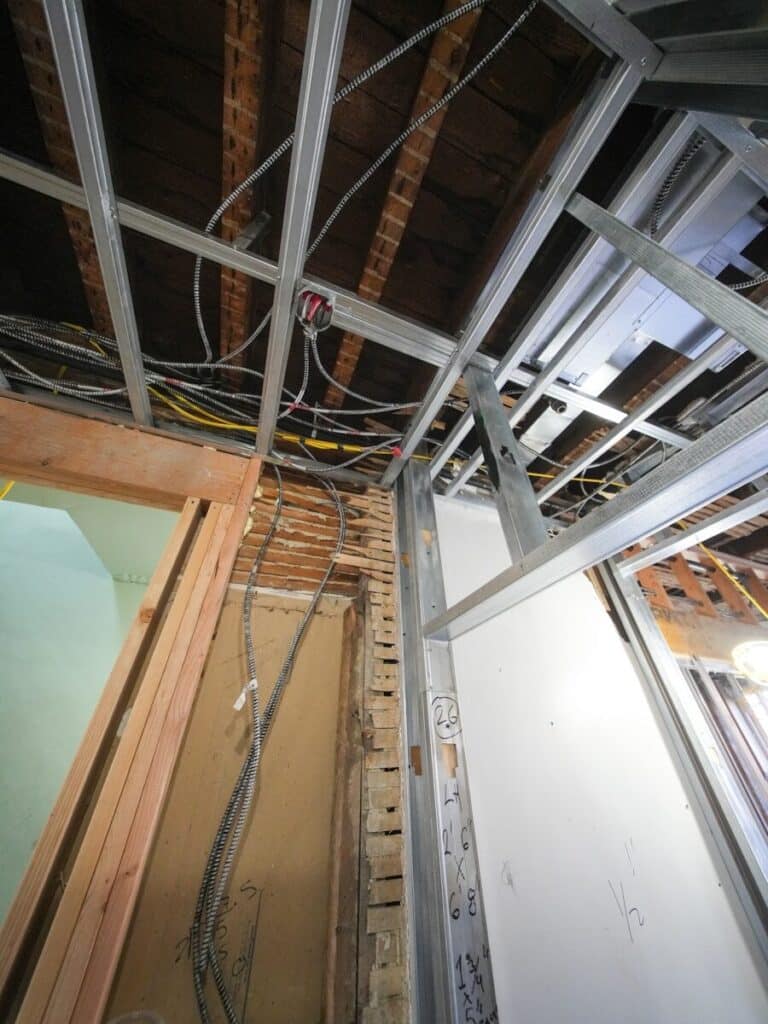 Exposed ceiling framework with wires and conduit.